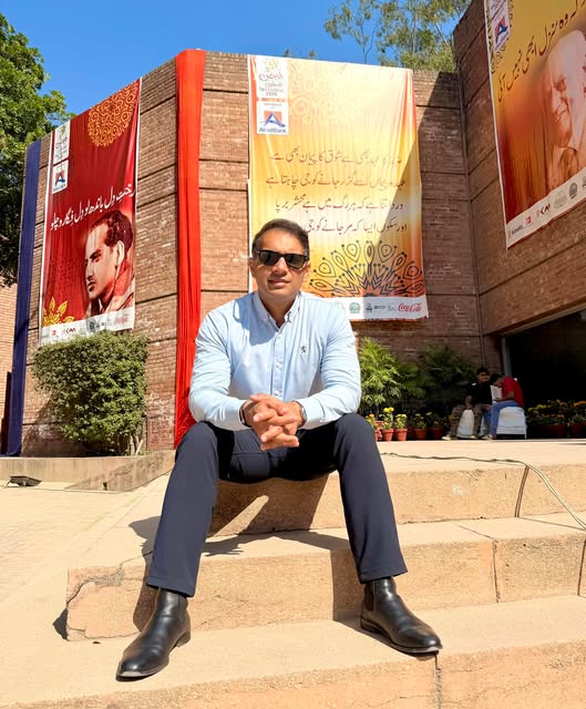Syed Umair Hassan seated on steps outside an arts event in Lahore