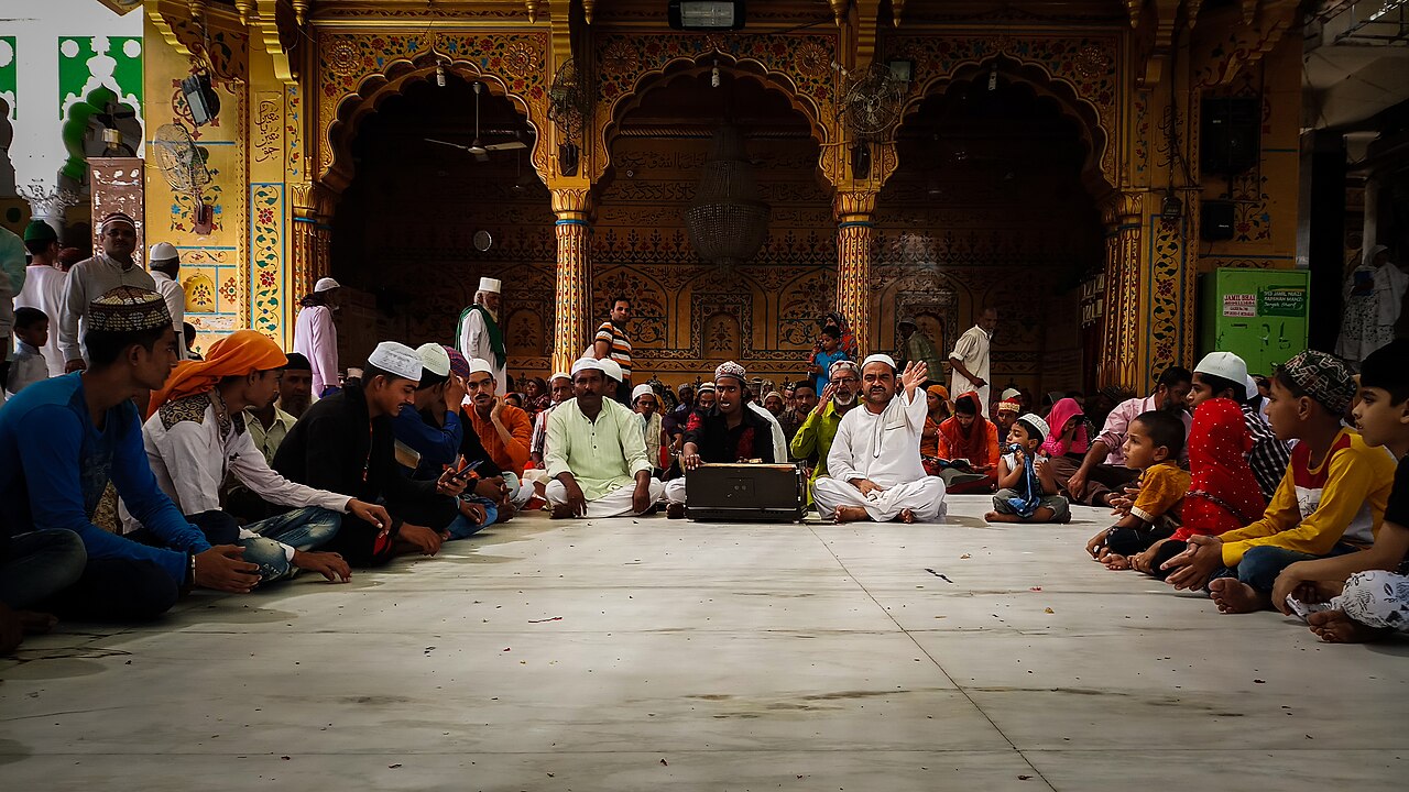 Qawwali musicians performing for a seated crowd in a shrine courtyard