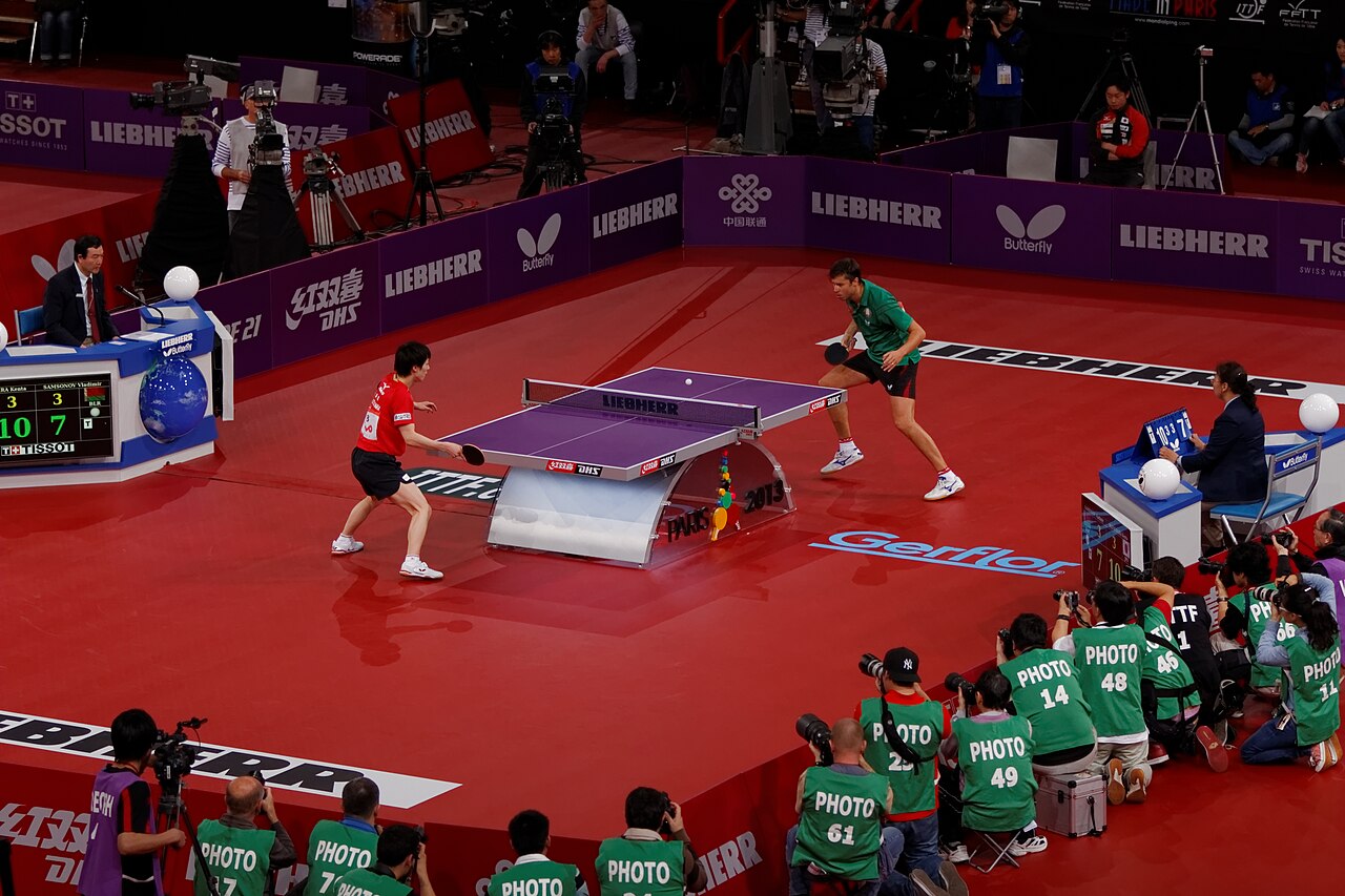 A table tennis player mid-rally at an international tournament